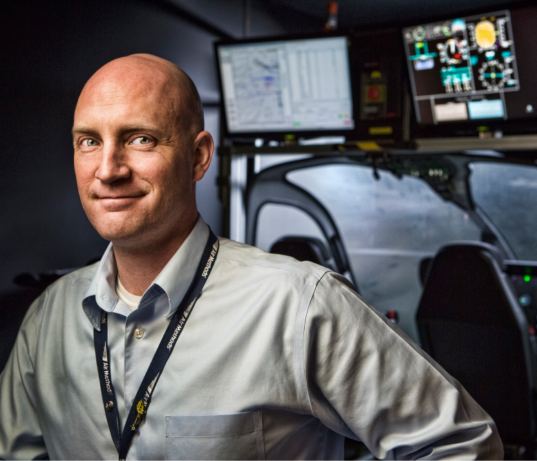 Air Methods employee standing in front of simulator. 